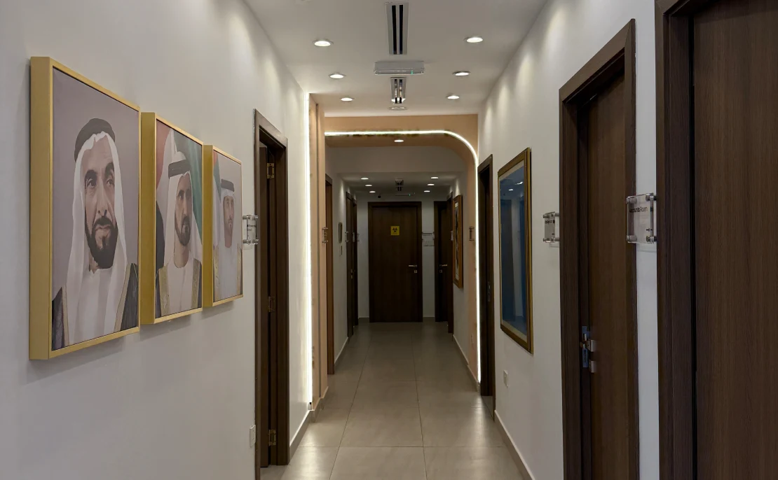 Luxury hallway at Halcyon Aesthetics Dubai featuring portraits of UAE leaders and professional treatment room access.