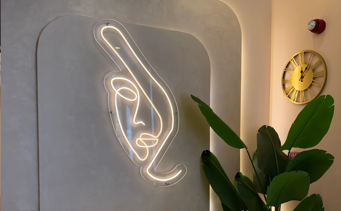 Elegant neon face art and luxury clinic interior at Halcyon Aesthetics Dubai, showcasing a modern and welcoming atmosphere.